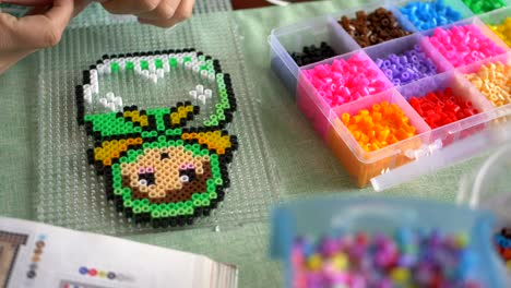 Ironing-beads-being-used-to-make-a-Babushka-figure-on-a-table,-close-up