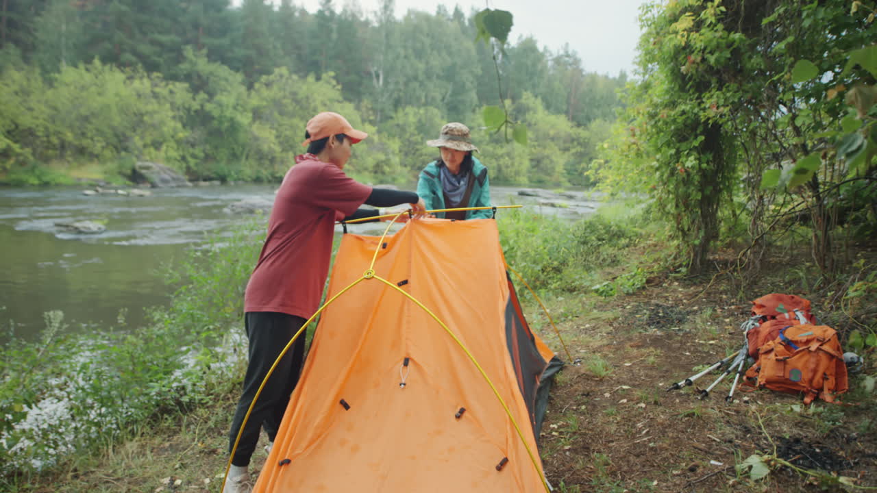 Turiste che montano la tenda sulla riva del fiume