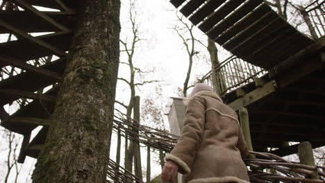 mujer mirando hacia la casa del árbol en el bosque