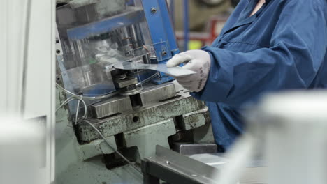 female worker wearing protective gloves working on a power press machine inside a modern factory close up low angle established