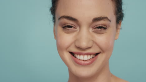 retrato en primer plano de una mujer joven y hermosa sonriendo con una piel hermosa y saludable que luce confiada belleza sensual sobre un fondo azul concepto de cuidado de la piel