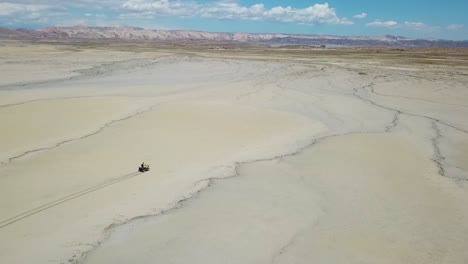 Vista-Aérea-De-Un-Vehículo-De-Cuatro-Ruedas-Que-Se-Mueve-Sobre-La-Arena-En-El-Desierto-De-Utah