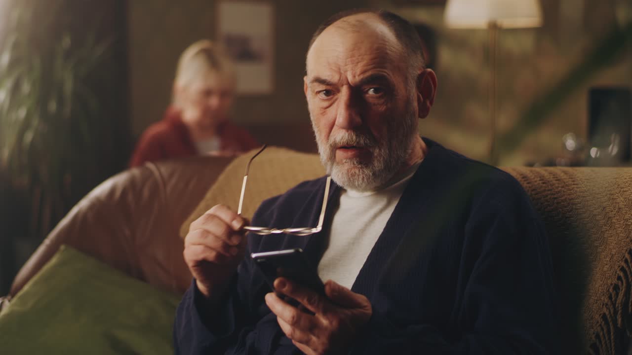 un anciano molesto con un teléfono inteligente.