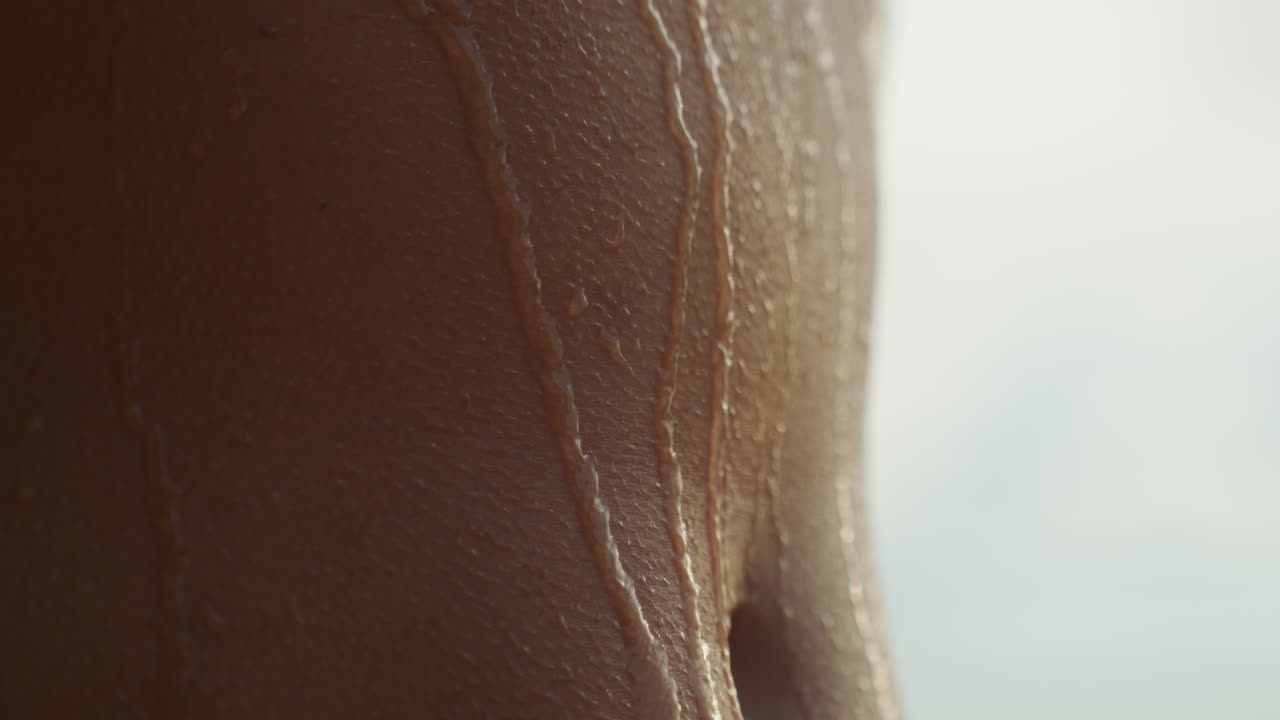 Agua fluyendo por un torso atlético, escena de ducha postentrenamiento, contornos musculares resaltados por una luz de fondo fría, gotas deslizándose lentamente, energía de estudio con un ambiente refrescante e intenso.