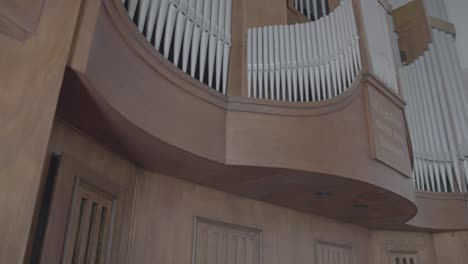 camera pans along a large organ in the gallery of a church, many organ pipes in the front