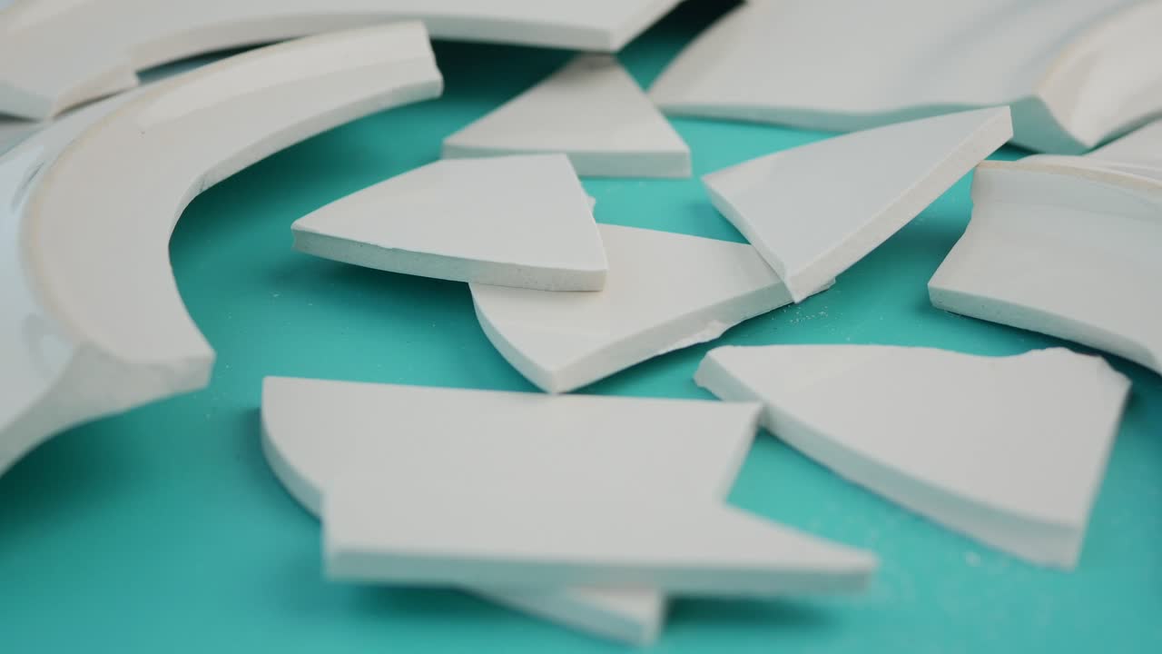 Broken White Plate Shards on Turquoise Background
