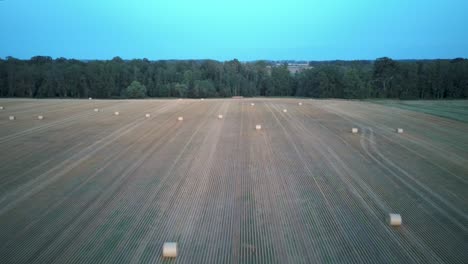 flying above the field with hay rolls sunrise.