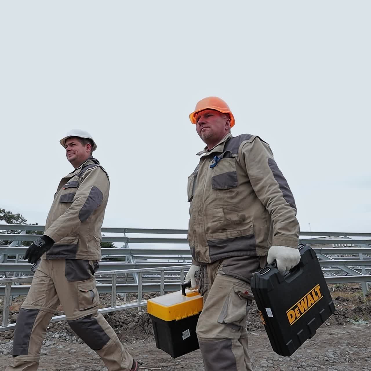Handsome men in uniform walking with instruments. Industry workers installing communications
