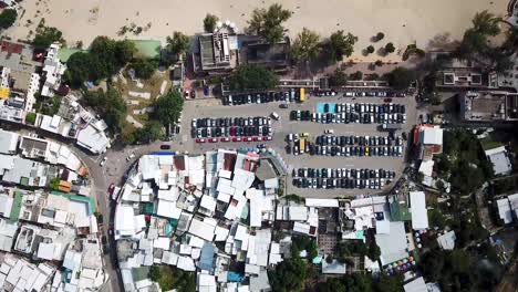 Una-Vista-Aérea-En-Movimiento-Del-Pueblo-De-Shek-O,-La-Playa-Y-De-Los-Visitantes-Que-Usan-Sombrillas-En-Hong-Kong-Mientras-Las-Playas-Públicas-Reabren-Al-Público,-Después-De-Meses-De-Cierre-En-Medio-Del-Brote-De-Coronavirus