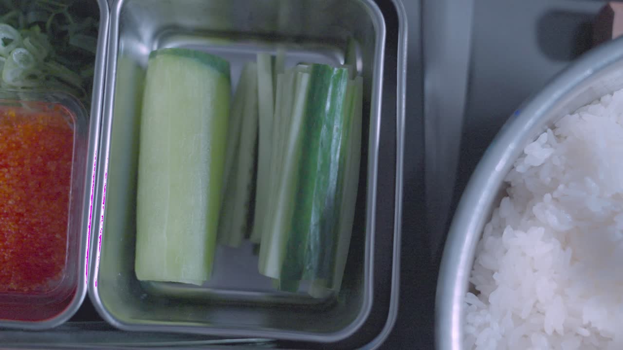 A sliding bird’s eye view showcasing multiple sushi ingredients, including fresh fish, rice, seaweed, and more, highlighting the essential components for sushi preparation.