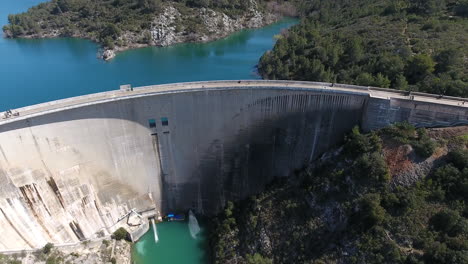 aerial zoom out over bimont dam with mountain in background, south of france