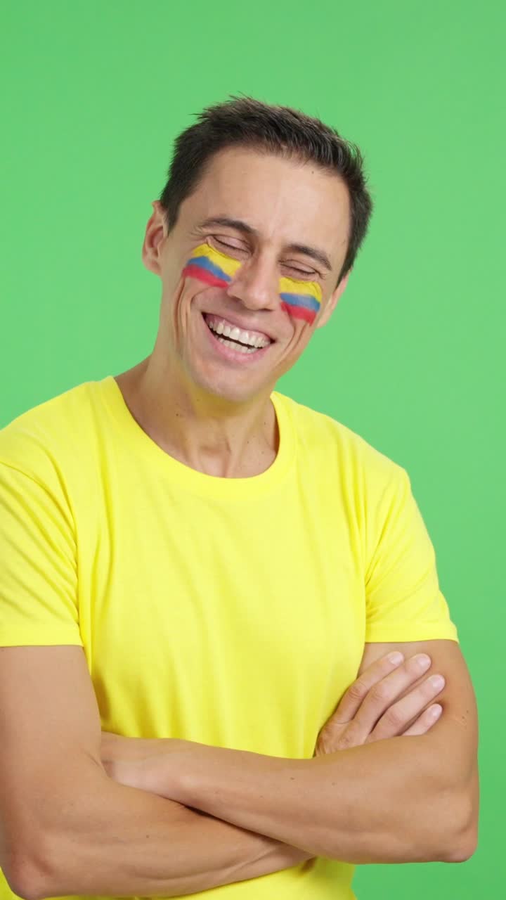 Homem feliz com a bandeira colombiana pintada no rosto, olhando para o lado.