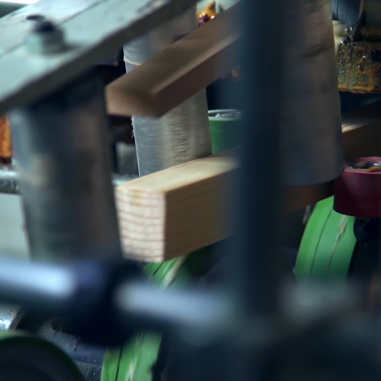 Timber bar in the automated machine. Rollers are rotating sending wooden block along conveyor belt. Close up