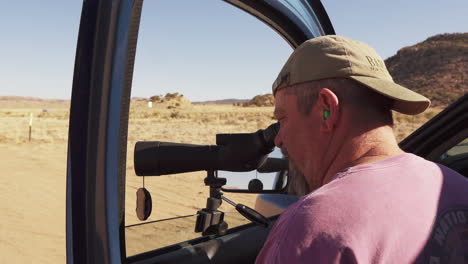 Male-Hunter-Looking-Through-Telescope,-Scouting-at-Colorado-Desert-Range
