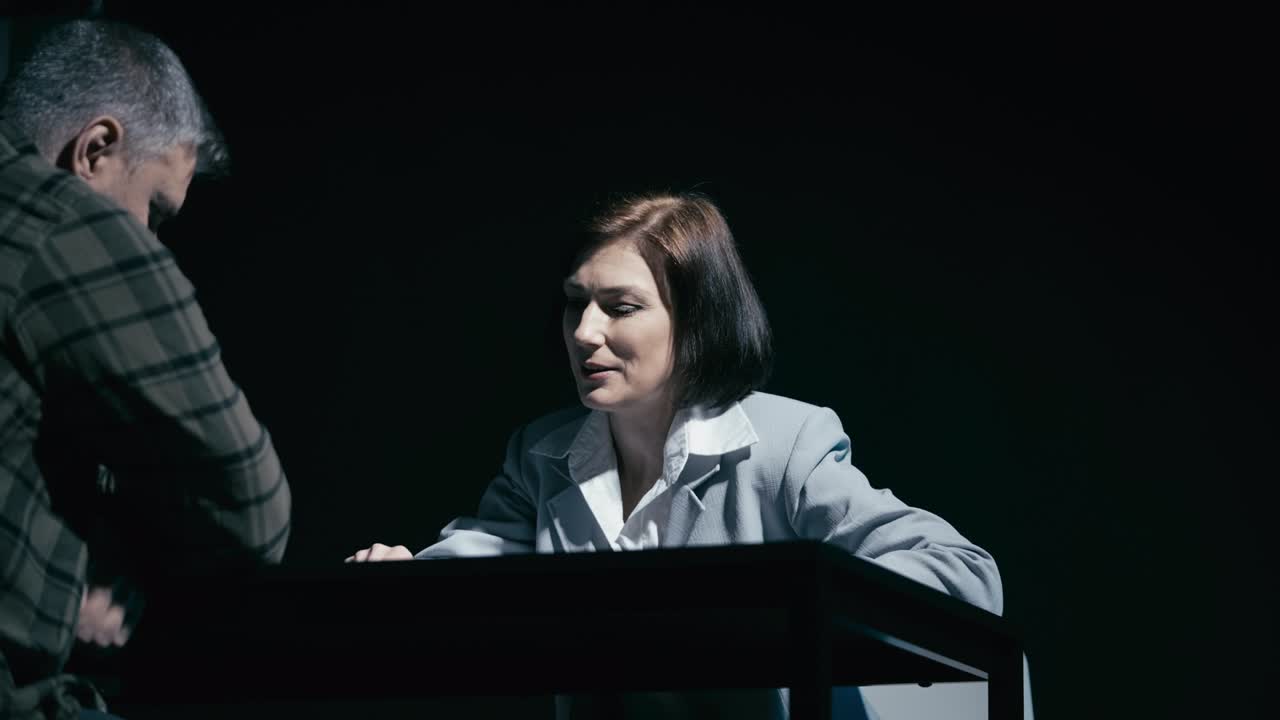 심각한 여성 탐정이 경찰에서 남성 용의자를 심문하고, 범죄 수사