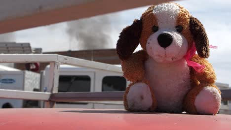 Small-plush-dog-sitting-in-front-of-a-burning-house-with-smoke