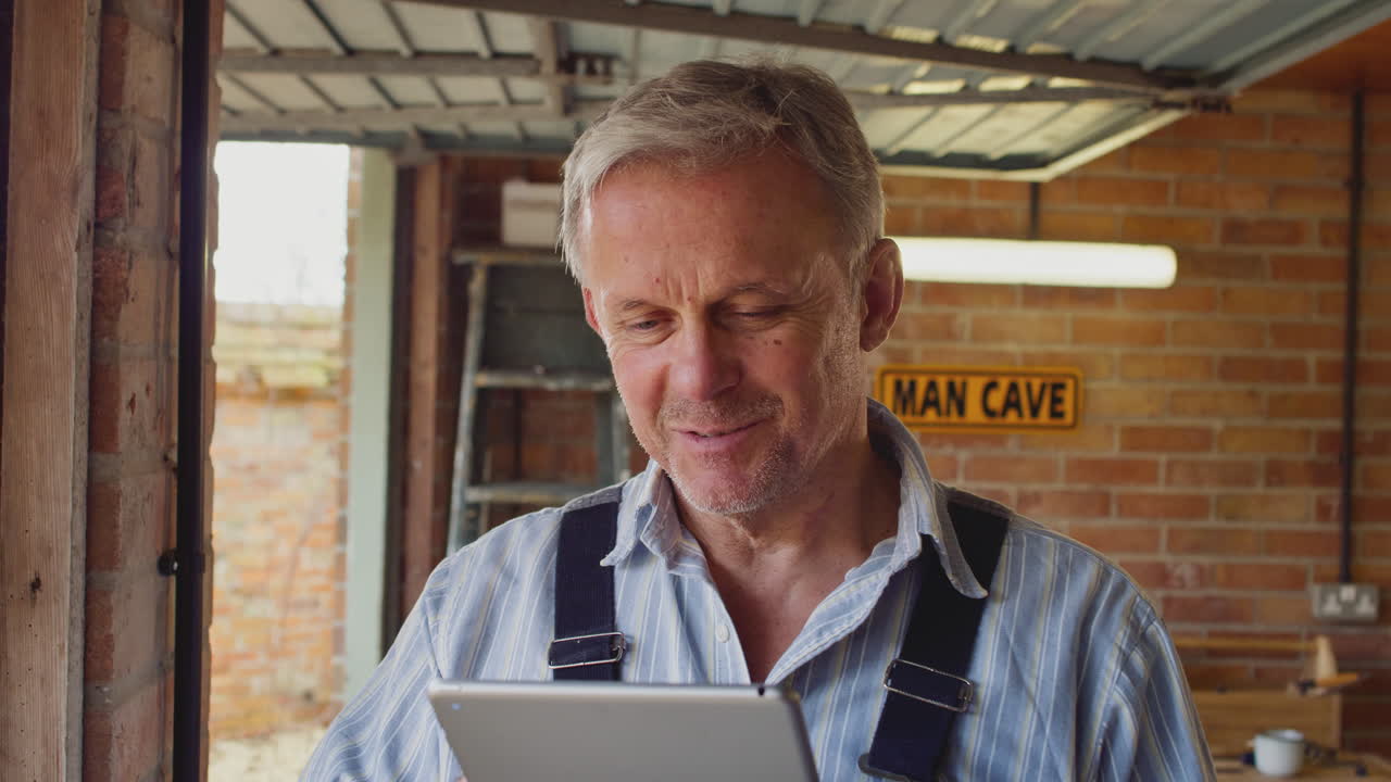 hombre maduro con mono usando una tableta digital en un taller de garaje