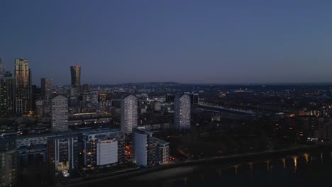 Aerial-over-River-Thames-toward-Docklands-and-Canary-Wharf-at-blue-hour