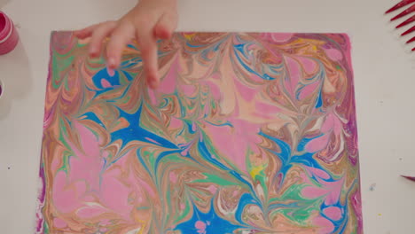 Little-girl-finger-points-to-painting-with-marbling-patterns