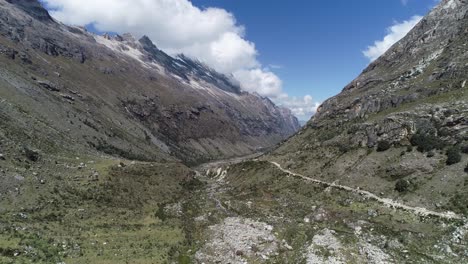 a breathtaking andean valley with a winding dirt path, rugged mountains, and a bright blue sky