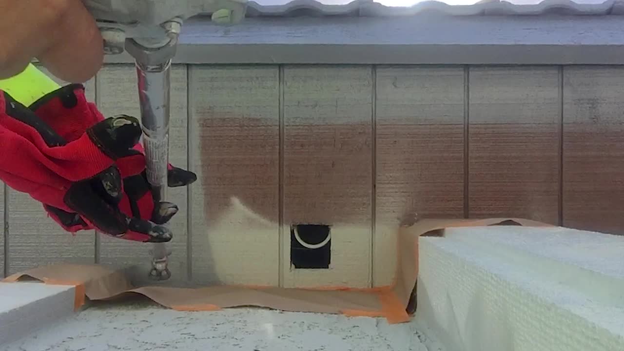 trabajador pintando el alero del techo con un rociador de pistola sin aire en un poste de extensión