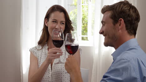 una pareja feliz bebiendo vino tinto