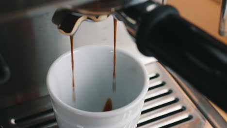 coffee gently flowing into espresso cup top view in slow motion