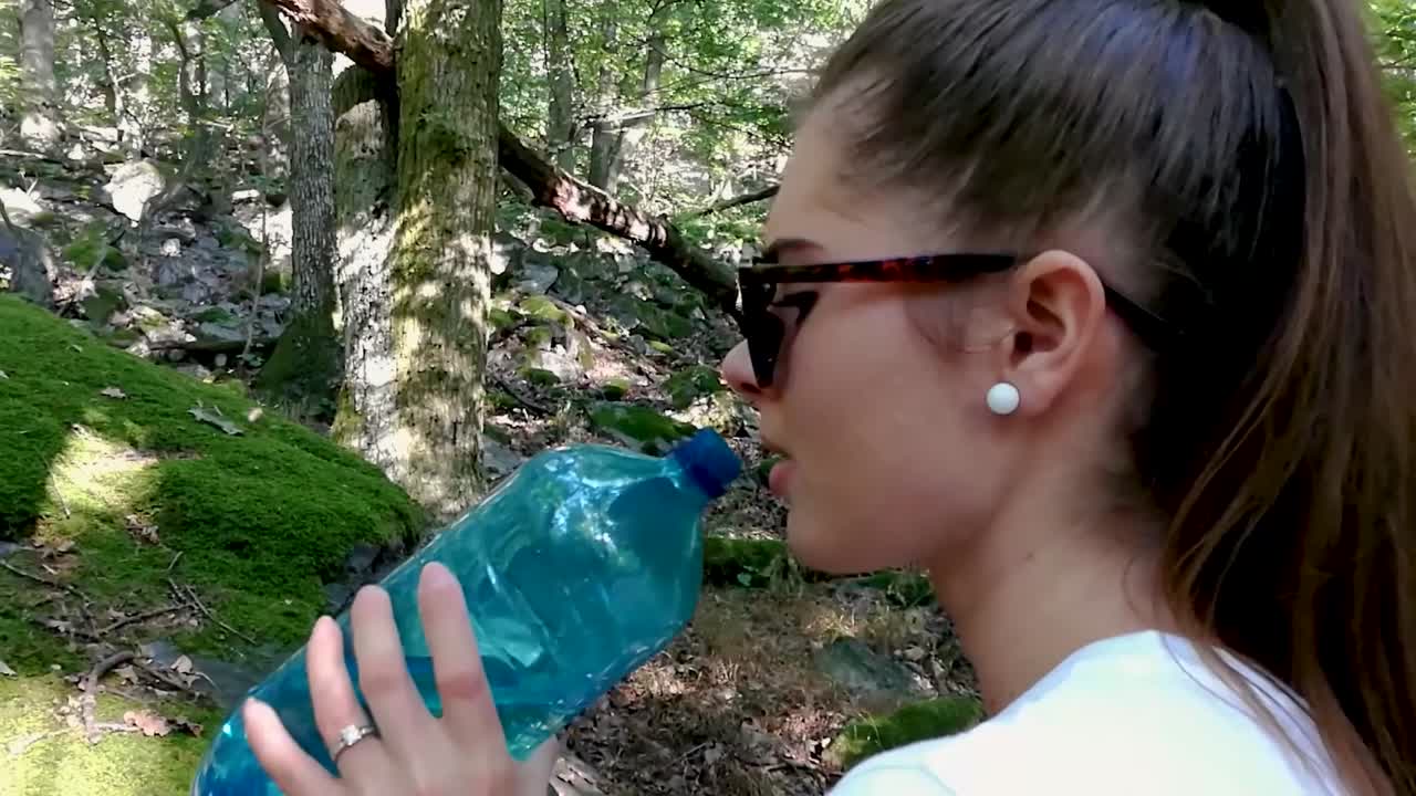 moscas del bosque e insectos que molestan a la joven tratando de beber agua de una botella azul en el bosque profundo, slomo, todavía