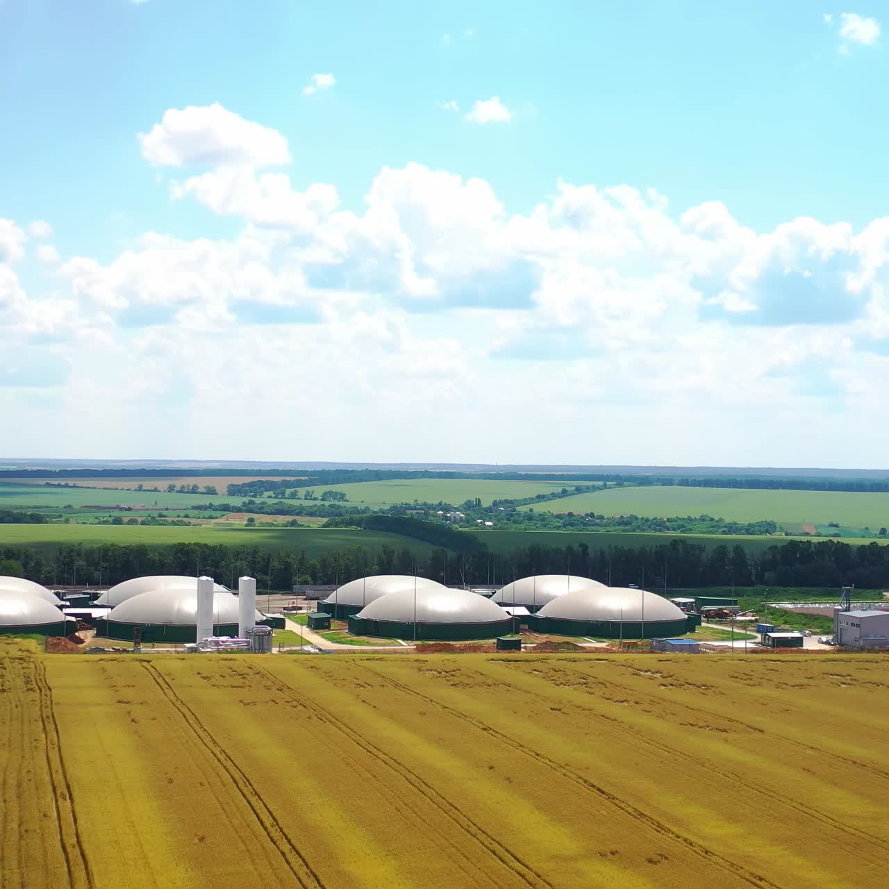 Innovative farm for bio production on field. Bio gas plant surrounded by nature in sunny day. Storage tanks for organic gas. Camera moving back