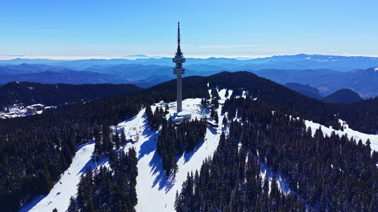 Veduta aerea di una torre di comunicazione in una stazione sciistica montana innevata.