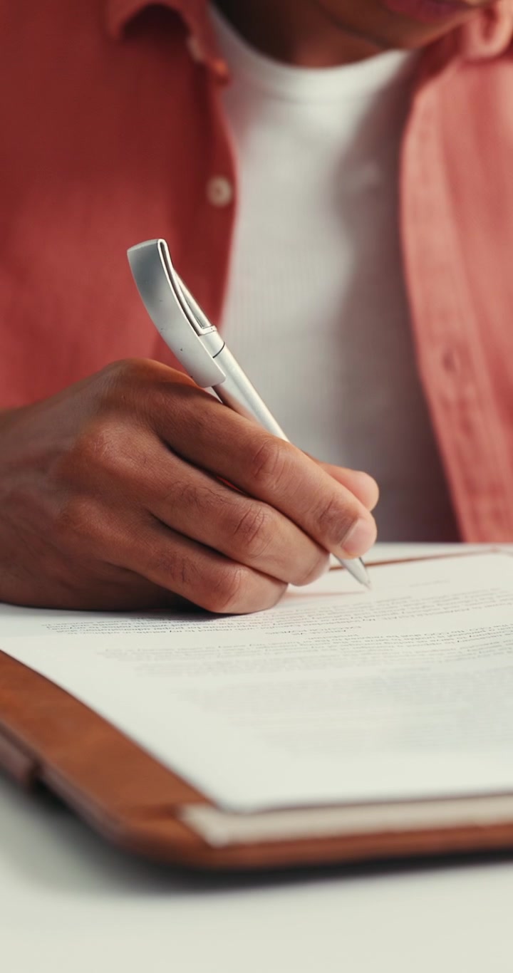 Persona che scrive su un documento con una penna