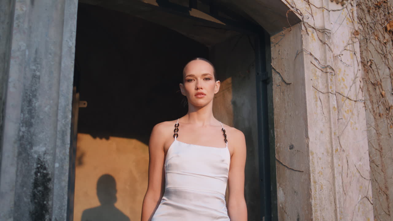 고대 건물을 포즈하는 여인 저녁 빛으로 조명. 아치에 서 있는 소녀