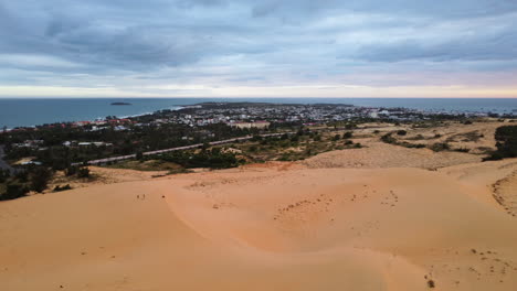 Dunas-De-Arena-Aérea-Paisaje-Marino-Costero-En-Mui-Ne-Vietnam,-Drones-Vuelan-Sobre-Un-Pequeño-Pueblo-De-Pescadores-Sobre-El-Océano-Durante-Un-Día-Nublado-Que-Revela-Un-Paisaje-Escénico