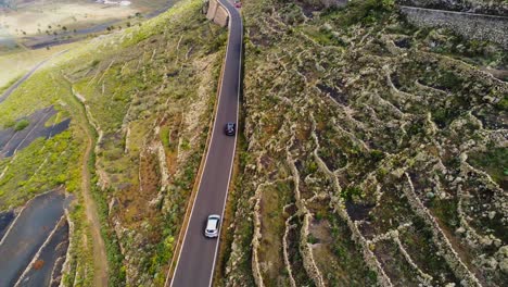 two cars driving on scenic mountain slope road in lanzarote island, aerial view