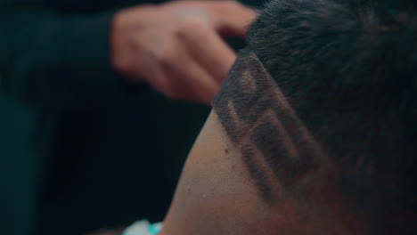 nice closeup slow motion shot of a professional barber while giving an artistic haircut with lines and shapes to a young client at his barbershop during the morning in 4k