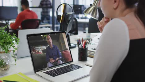 Caucasian-woman-having-a-video-call-with-male-office-colleague-on-laptop-at-office