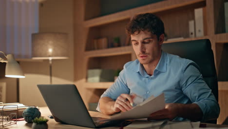 late worker typing laptop busy of overtime work close up. man holding documents