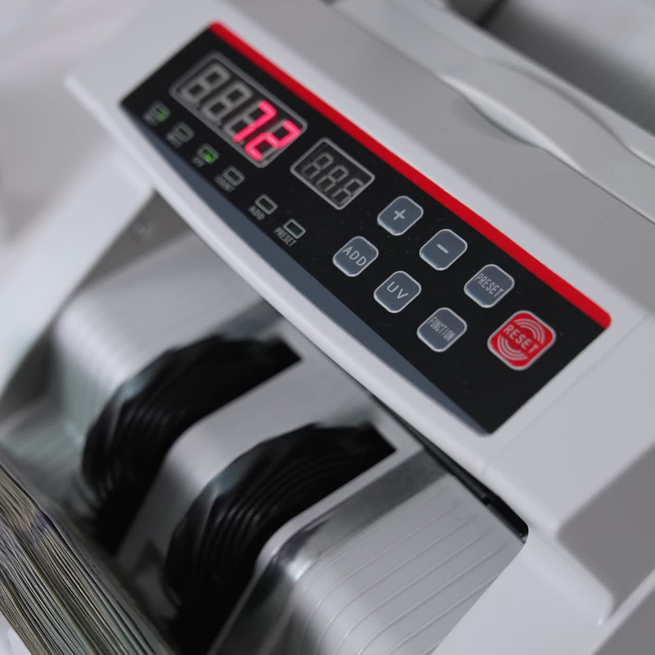 Male hand inserts a wad of hundred dollar bills into a slot of cash counting machine. Equipment for financial operations close up. Blurred backdrop