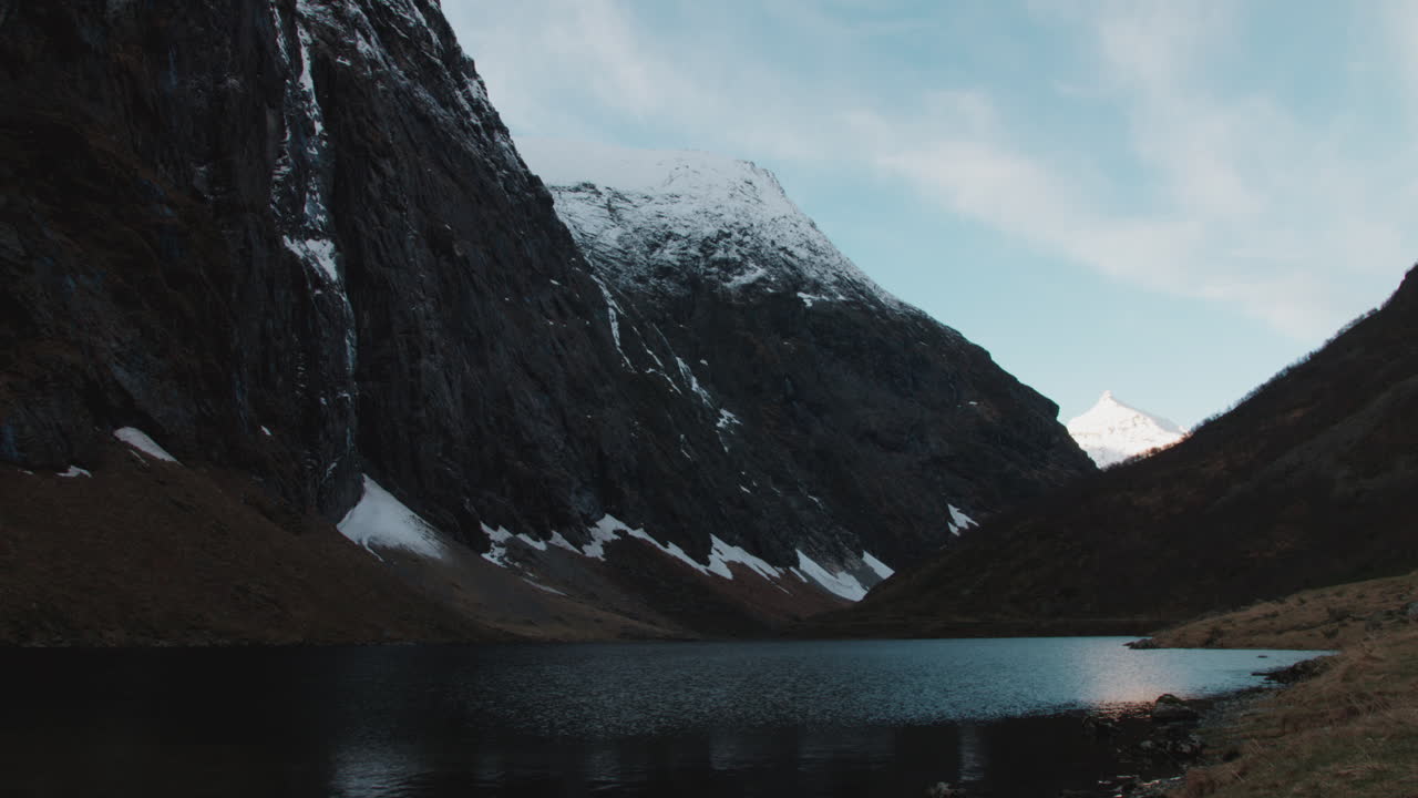 Scenic shot of Norangsdalen, a valley in Norway with tall mountains, steep cliffs and a lake with snow covering the peaks on a sunny winter day
