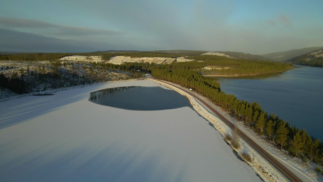 заснеженное озеро, дорога, окруженная с двух сторон озером, аэрофотосъемка