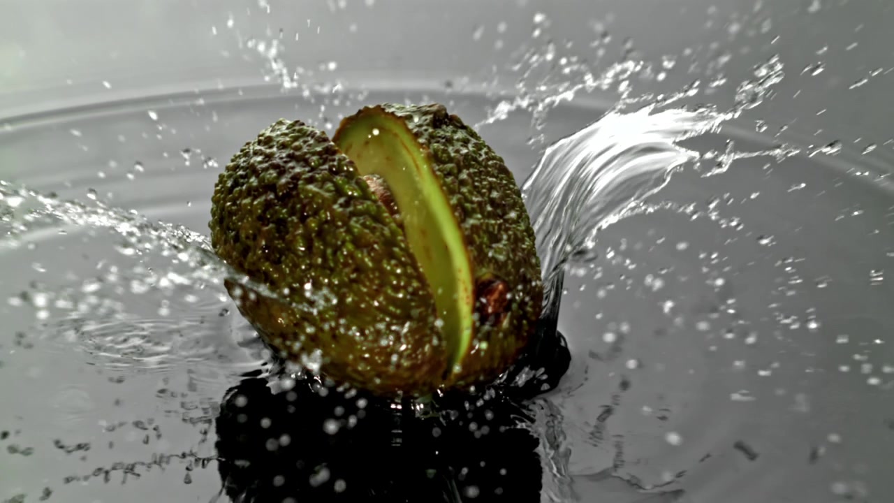 Movimento rallentato di avocado che cade e si spacca nell'acqua