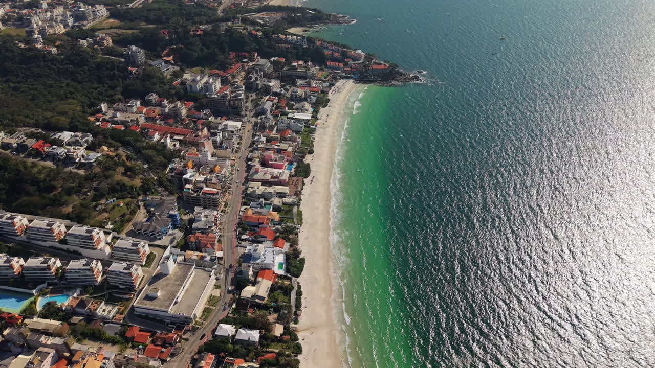 Flying over Praia Bombinhas beach and blue sea coastline, Brazil