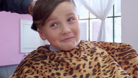 Young-boy-in-barbershop,-combing-hair,-funny-bored-or-scared-face-closeup-view