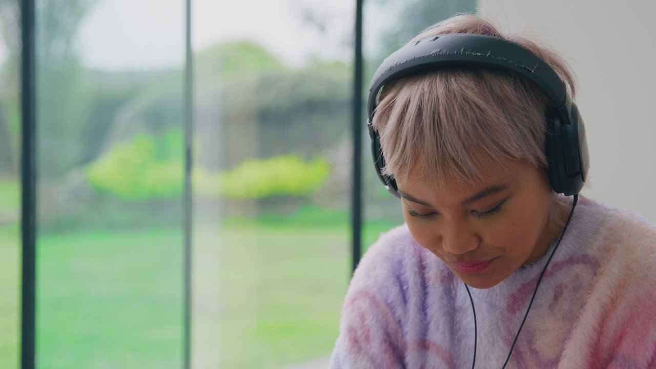 마이크와 헤드폰을 착용한 여성 블로거가 휴대전화를 보고 라이브 스트리밍을 하고 있습니다.