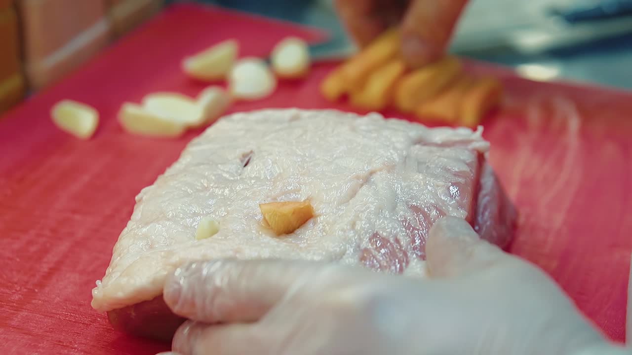 요리사는 고기 조각에 마늘과 당근 조각을  ⁇ 입합니다.