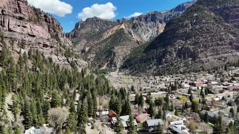 estableciendo la toma de una pequeña ciudad rodeada de pinos y montañas, cielo azul con nubes a finales de la primavera, ouray colorado