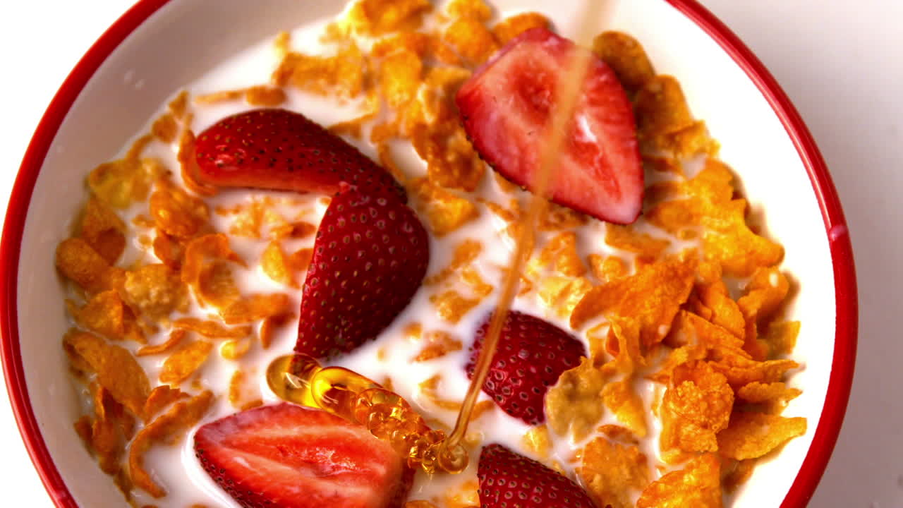 Miele che cola su una ciotola di cereali con fragole
