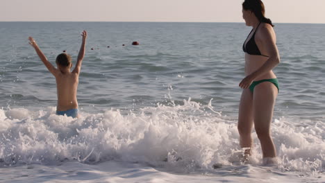 mother and son playing in the waves at the beach