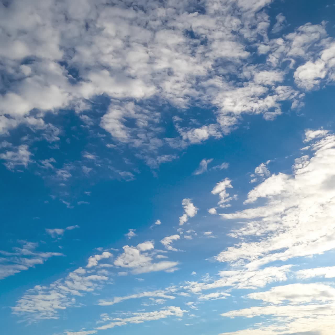 Beautiful light spindrift clouds fly away opening blue skies. Sun rays coming through the clouds. Timelapse view from below