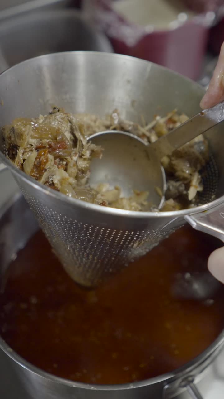 Straining food ingredients through a metal sieve into a pot